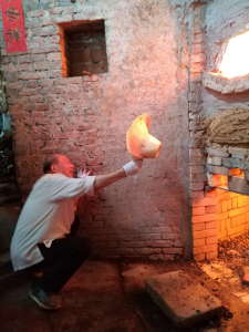 胡家旺在复建的古法柴窑窑口看火